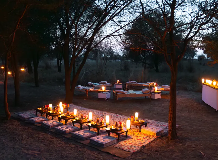 Candlelit low tables set for dinner under the trees